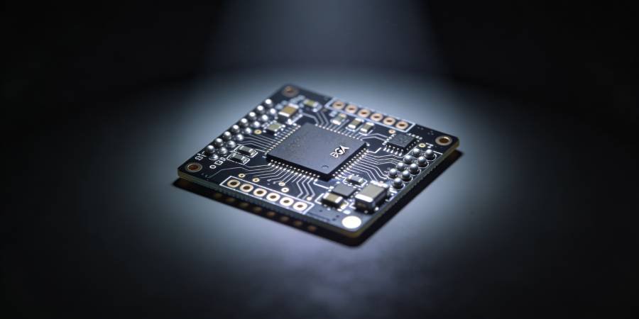 Compact HDI multilayer PCB prototype with microvias and BGA packages under a soft spotlight on a dark background.
