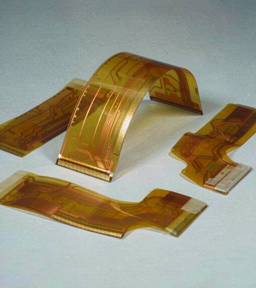 Illustration of unpopulated amber flex PCB prototypes with exposed gold contact pads and local stiffener backing