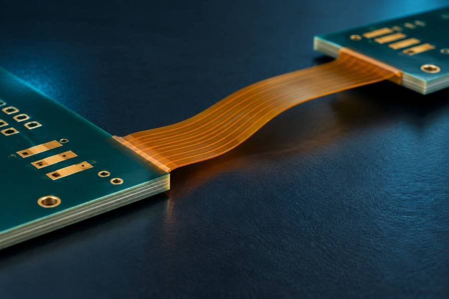 Rigid-flex PCB with an amber polyimide bridge and a smooth bend away from the rigid board edge