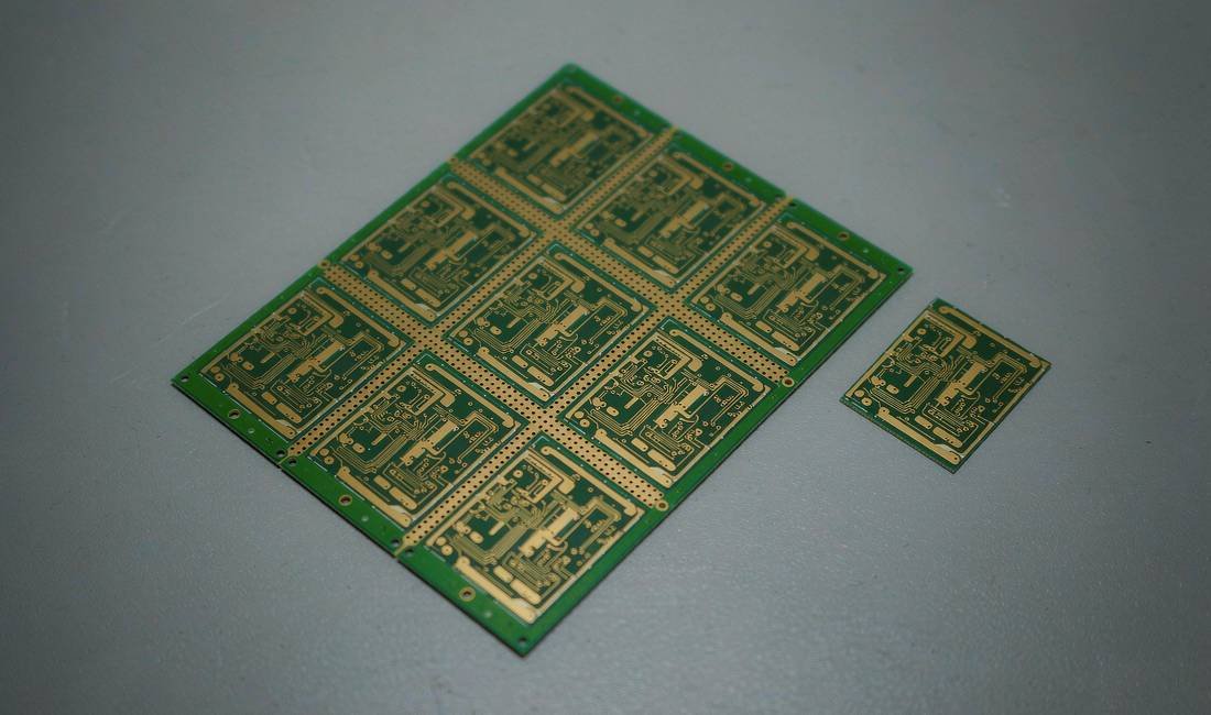 Small PCB fabrication panel beside a matching individual bare board